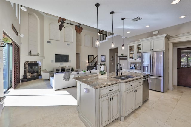 kitchen with glass insert cabinets, light stone countertops, visible vents, appliances with stainless steel finishes, and a sink