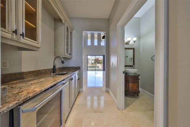kitchen with dark stone countertops, glass insert cabinets, light tile patterned floors, a sink, and cream cabinetry