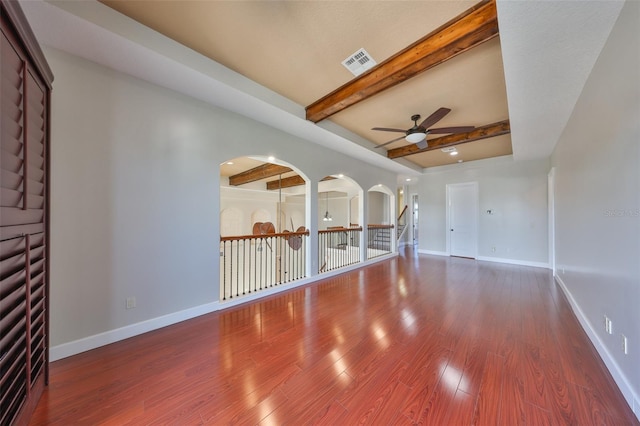 unfurnished living room with baseboards, visible vents, beam ceiling, ceiling fan, and wood finished floors