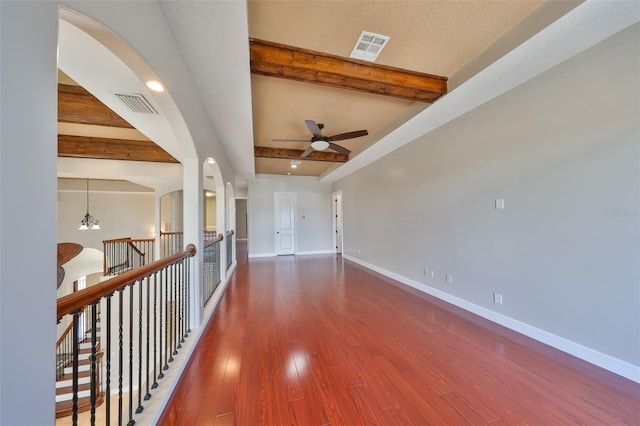interior space with beamed ceiling, ceiling fan, visible vents, wood finished floors, and baseboards