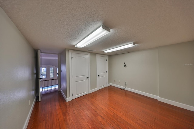 bonus room with a textured ceiling, wood finished floors, and baseboards