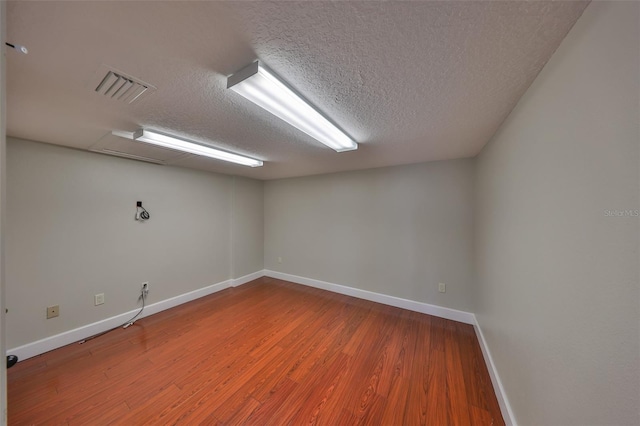 unfurnished room featuring visible vents, baseboards, wood finished floors, and a textured ceiling