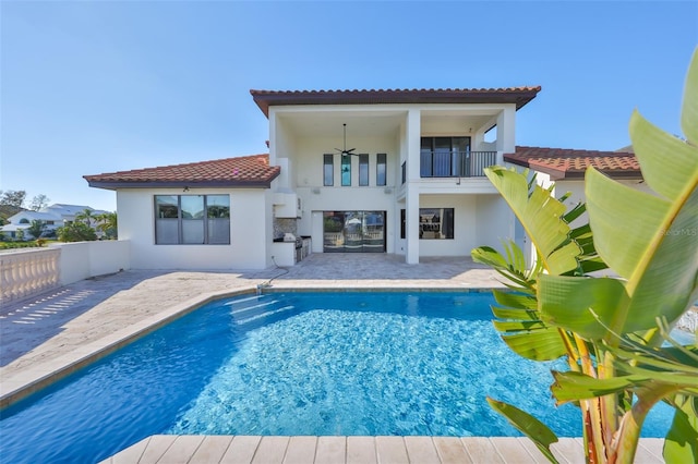 rear view of property with a tiled roof, ceiling fan, stucco siding, a patio area, and an outdoor pool