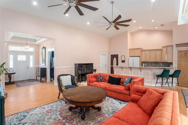 living area featuring light wood finished floors, visible vents, a wainscoted wall, high vaulted ceiling, and recessed lighting