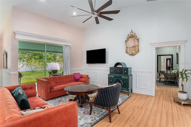 living area with visible vents, a decorative wall, wainscoting, ceiling fan, and wood finished floors