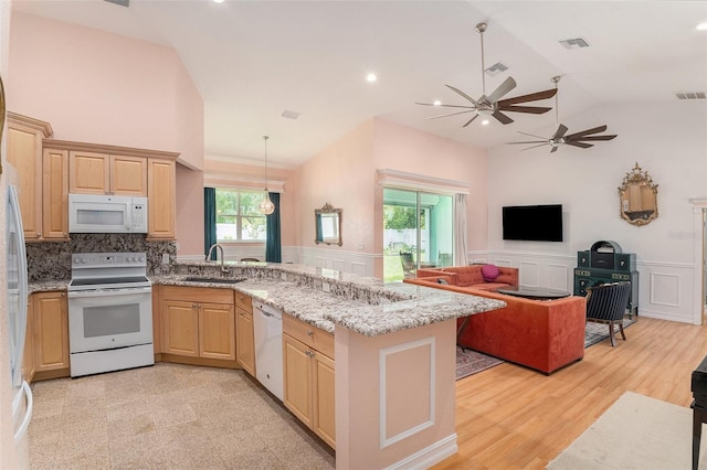 kitchen with visible vents, wainscoting, a sink, white appliances, and a peninsula