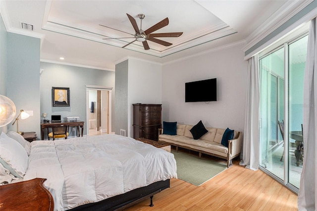 bedroom with a tray ceiling, visible vents, ornamental molding, wood finished floors, and access to outside