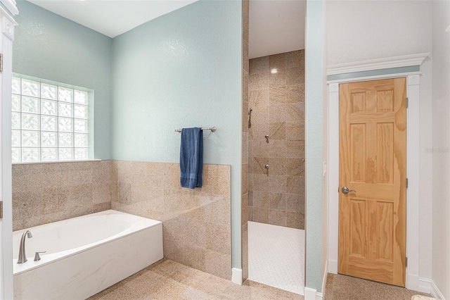 bathroom featuring a walk in shower, a garden tub, and tile walls