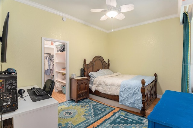 bedroom with ceiling fan, a closet, wood finished floors, and crown molding