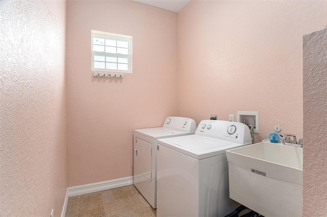 laundry room featuring washing machine and clothes dryer, a textured wall, a sink, laundry area, and baseboards