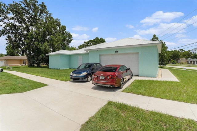 view of side of property with metal roof, a garage, driveway, a yard, and stucco siding