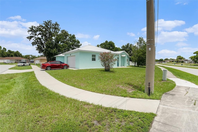 view of side of home featuring a garage, a lawn, and stucco siding