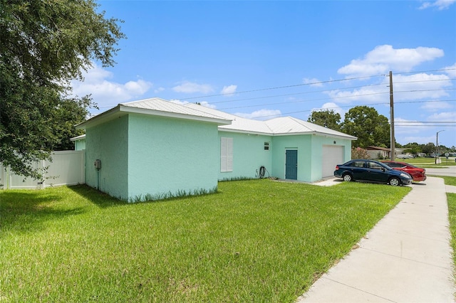 view of front of property with a garage, a lawn, fence, and stucco siding