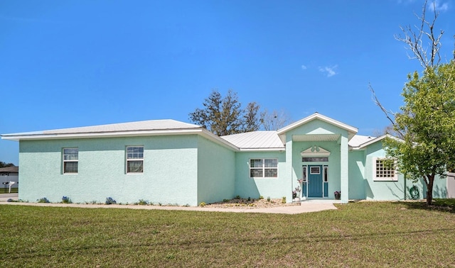 ranch-style house with stucco siding, metal roof, and a front yard