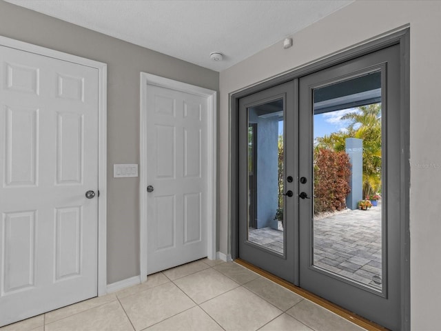 doorway with french doors, a textured ceiling, and light tile patterned floors