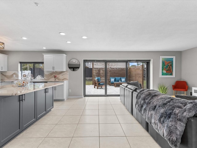 interior space with light stone counters, tasteful backsplash, light tile patterned floors, gray cabinets, and white cabinets