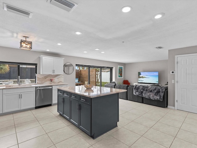 kitchen featuring sink, light tile patterned floors, dishwasher, white cabinetry, and a kitchen island