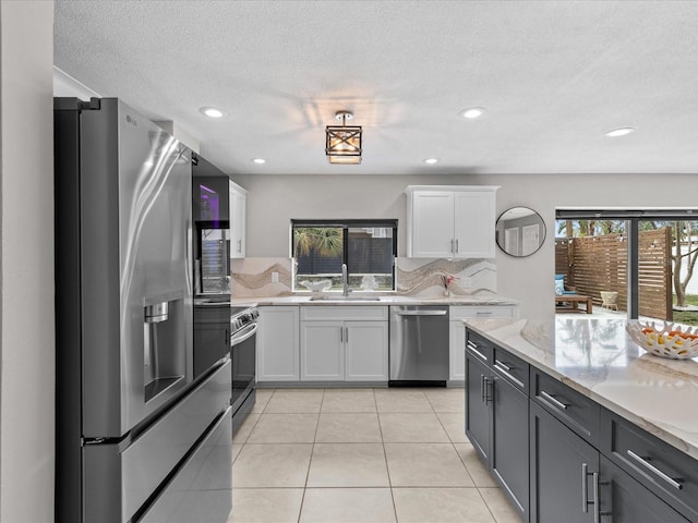 kitchen with sink, white cabinetry, tasteful backsplash, light tile patterned floors, and stainless steel appliances