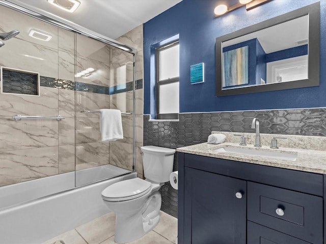 full bathroom with tile walls, shower / bath combination with glass door, tile patterned flooring, vanity, and toilet