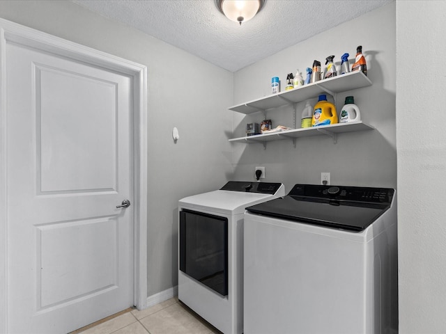 clothes washing area featuring separate washer and dryer, light tile patterned floors, and a textured ceiling