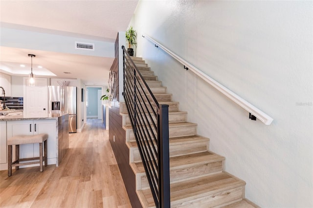 staircase featuring hardwood / wood-style floors and a raised ceiling