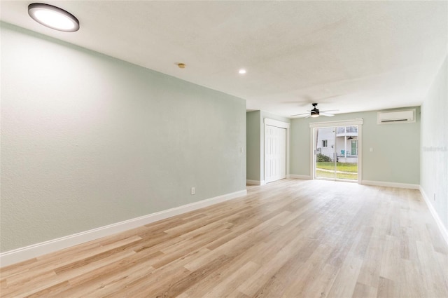 empty room featuring ceiling fan, a wall mounted air conditioner, and light hardwood / wood-style flooring