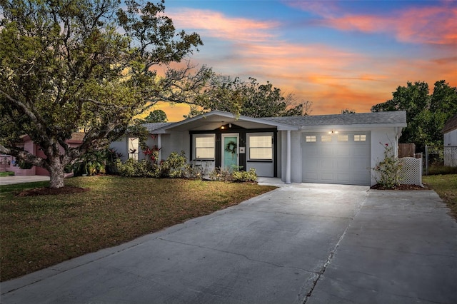 single story home featuring a garage, concrete driveway, and a yard