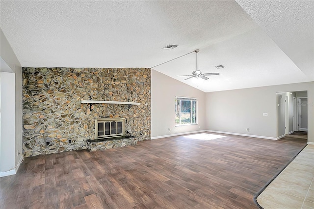 unfurnished living room with vaulted ceiling, a textured ceiling, dark hardwood / wood-style floors, ceiling fan, and a fireplace