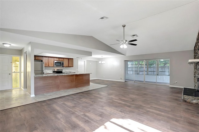 kitchen featuring vaulted ceiling, appliances with stainless steel finishes, kitchen peninsula, light hardwood / wood-style floors, and ceiling fan with notable chandelier