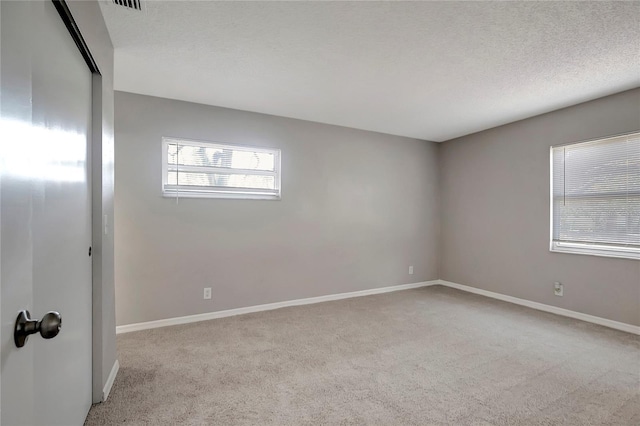 carpeted empty room featuring a textured ceiling