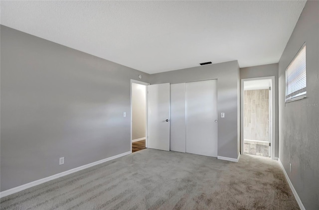 unfurnished bedroom with light colored carpet and a closet