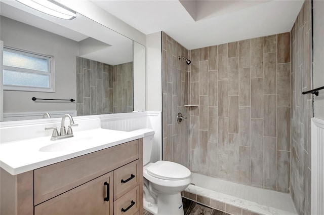 bathroom with vanity, tiled shower, and toilet