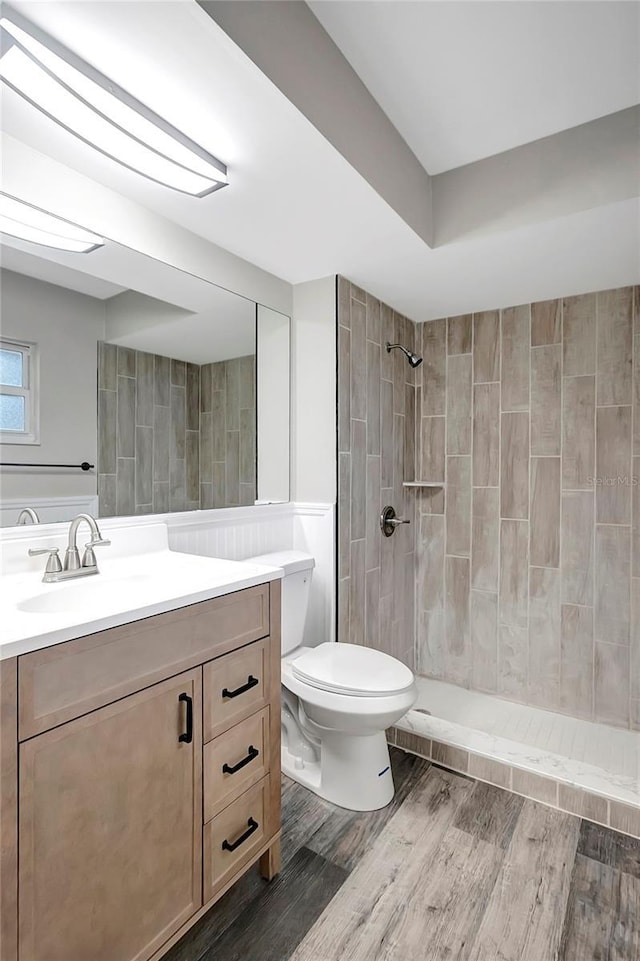 bathroom featuring tiled shower, vanity, toilet, and wood-type flooring