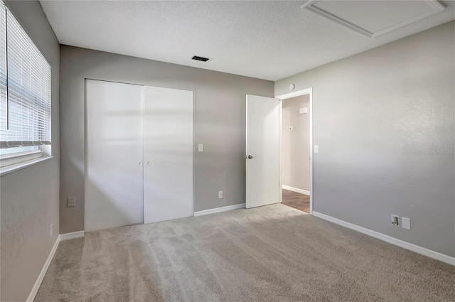 unfurnished bedroom featuring light carpet, a closet, and a textured ceiling