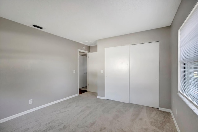 unfurnished bedroom featuring light colored carpet and a closet