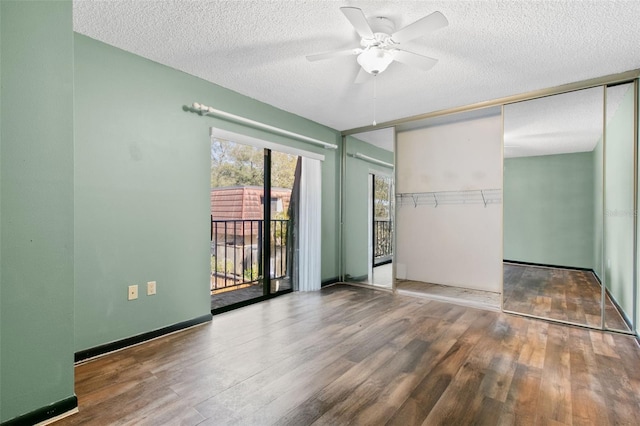 unfurnished bedroom featuring wood-type flooring, access to exterior, a textured ceiling, and a closet