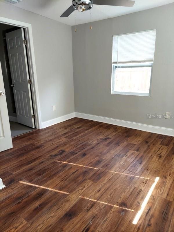 empty room with ceiling fan and dark hardwood / wood-style flooring