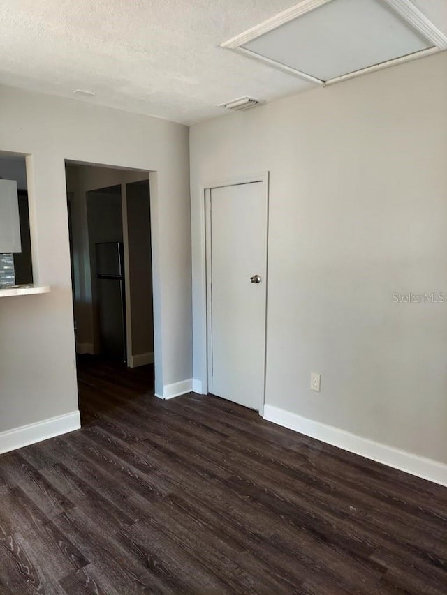 spare room with a textured ceiling and dark hardwood / wood-style flooring