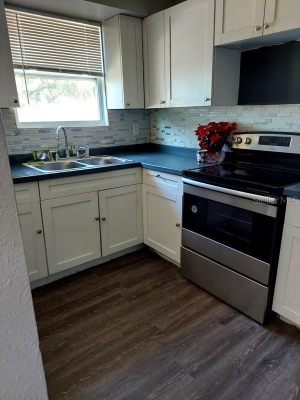 kitchen featuring white cabinetry, sink, decorative backsplash, dark wood-type flooring, and stainless steel electric range