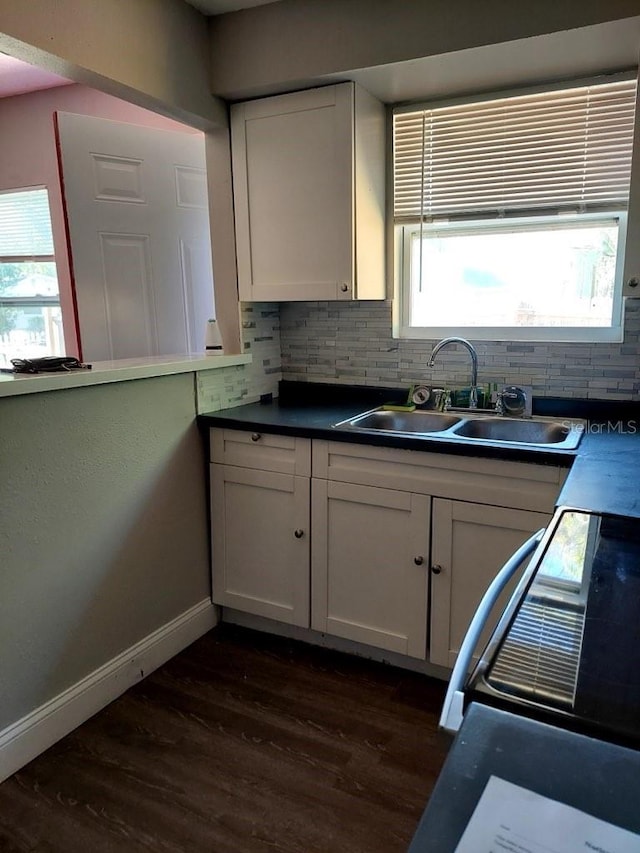 kitchen with dark hardwood / wood-style floors, white cabinetry, sink, decorative backsplash, and range