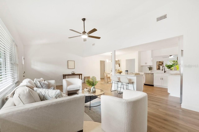 living room featuring vaulted ceiling, ceiling fan, and light wood-type flooring