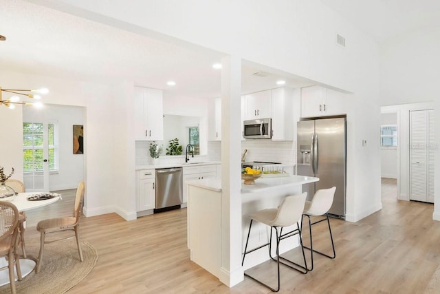 kitchen with white cabinetry, appliances with stainless steel finishes, sink, and light wood-type flooring