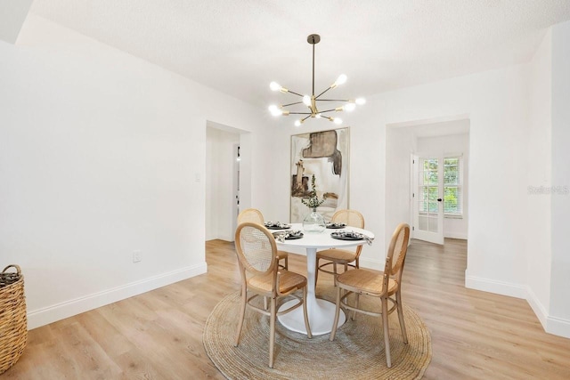 dining room featuring a textured ceiling, light hardwood / wood-style flooring, and a notable chandelier