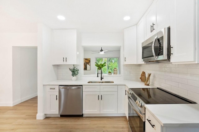 kitchen with light wood-type flooring, stainless steel appliances, sink, and white cabinets