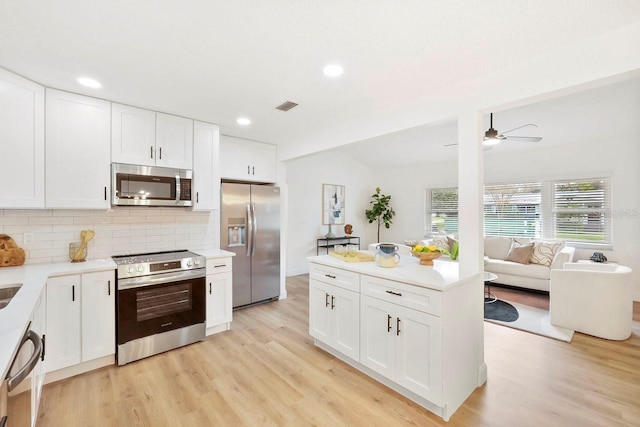 kitchen with appliances with stainless steel finishes, white cabinets, and light hardwood / wood-style flooring