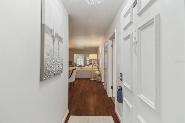 corridor with a textured ceiling and dark hardwood / wood-style flooring