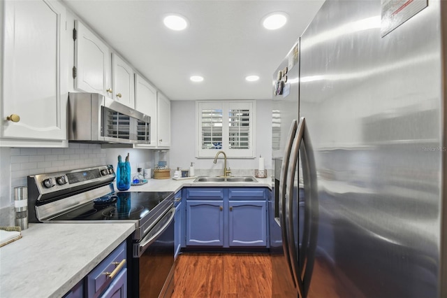 kitchen with sink, white cabinetry, blue cabinetry, stainless steel appliances, and dark hardwood / wood-style flooring