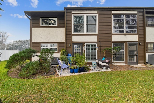 rear view of house with a lawn and central AC unit