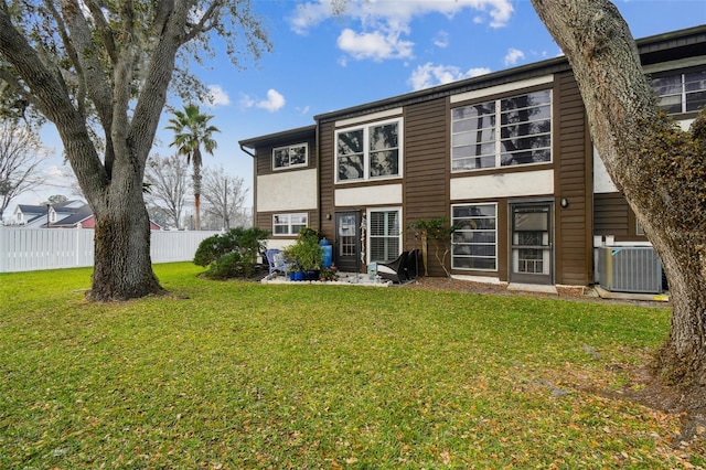 back of property with cooling unit, a lawn, stucco siding, and fence