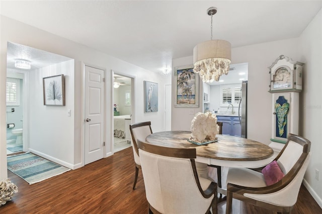 dining space featuring dark wood-style floors, baseboards, and a notable chandelier